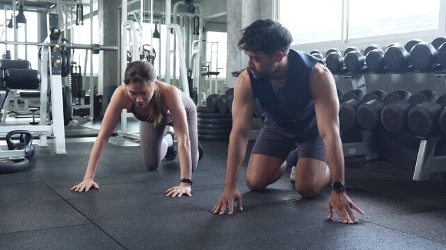 Fit young couple doing push-ups together in a modern gym, strength training, bodyweight exercise, fitness, healthy lifestyle, workout motivation, and active living.