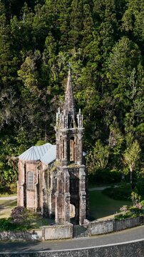 Historic chapel in forest in Sao Miguel, Azores, Portugal. Vertical aerial footage of Nossa Senhora das Vitorias Chapel in Furnas with neo-Gothic facade