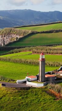 Lighthouse on cape Cintrao with Cliffs and Green Fields and Atlantic Ocean. Azores, Sao Miguel Island, Aerial View