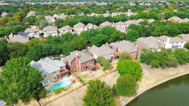 Private swimming pool sits behind residential property overlooking canal bank. Lush trees frame backyard spaces plus rooftops within Valley Ranch mature tree canopy,, Valley Ranch, Irving, Texas