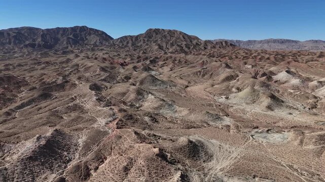 Aerial view of arid valley with rolling hills and rugged terrain