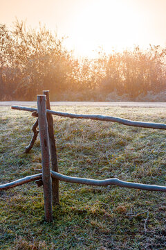 autumnal rural landscape in fog. countryside scenery with wooden fence in morning light. farm field by the road in hoarfrost