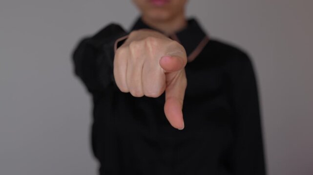 Young business woman points at the camera with a strong direct gesture, symbolizing attention, choice, and personal communication