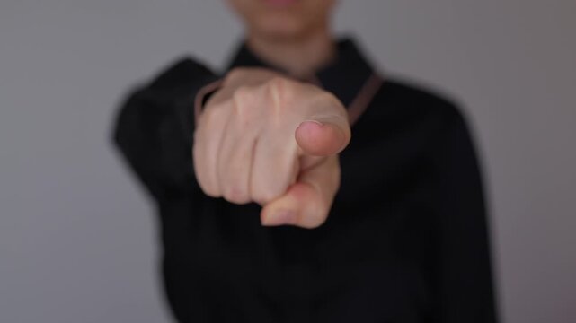 Young business woman points forward at the viewer, creating a direct and engaging gesture that communicates focus and personal address