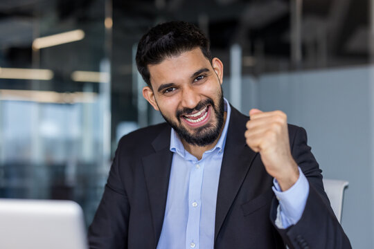 Happy young businessman celebrating success and achievement in office