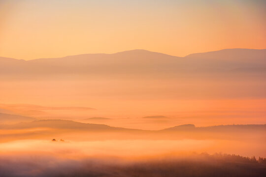 cold morning fog with red hot sunrise in the Carpathian mountains. rural valley of Perechyn district in morning mist. nature background with fog rolling over hillls