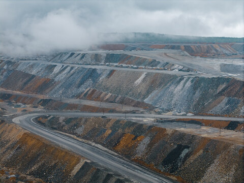 Open pit mine terraced slopes with winding haul road, mining industry aerial view