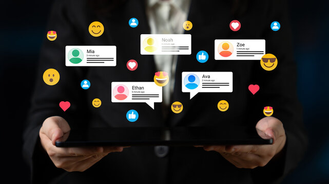 A businesswoman holds a tablet displaying social media comments, showcasing digital interaction and engagement in modern professional environments with colorful emojis. Ledger