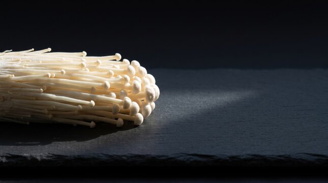 Fresh White Enoki Mushrooms on Black Slate.
