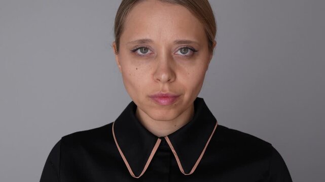 Young business woman looks forward with a serious face and nods in approval, showing agreement, confidence, and calm professional business attitude in a studio portrait