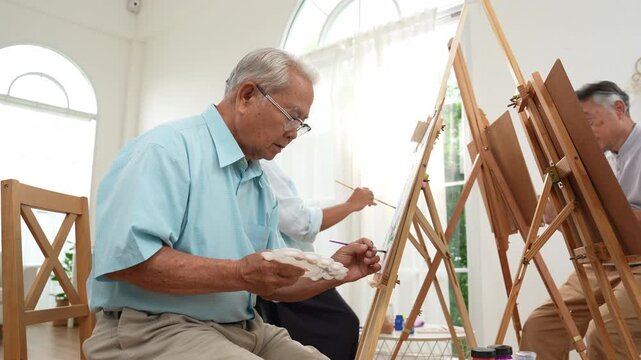 Group of elderly Asian friends enjoying a painting class at home, creating art together in a warm setting. Active aging, creativity, social connection, wellbeing, and senior lifestyle.