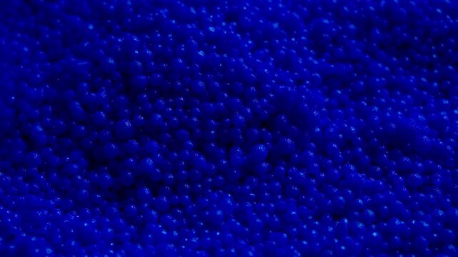 High-quality macro footage of blue plastic pellets falling in slow motion. Perfect for industrial manufacturing, chemical engineering, material science, and recycling economy concepts. 
