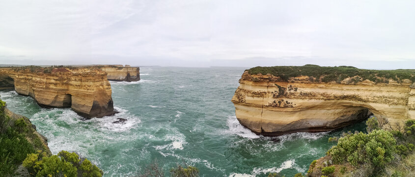 Panoramic view of eroded limestone cliffs and rock arches above turquoise sea along the Great Ocean Road, Victoria, Australia