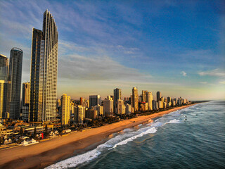 Aerial view at sunrise over Gold Coast skyscrapers along Surfers Paradise beach with golden light, waves and blue sky, Queensland, Australia © Florian