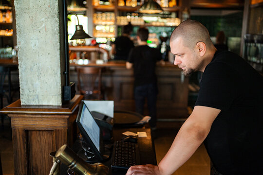 Manager looking at computer screen, working at a restaurant or cafe bar
