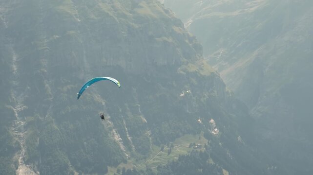 Tandem paragliding flight over Grindelwald near First mountain, Switzerland. Professional pilot and passenger flying above scenic alpine landscape. Concept of adventure tourism, outdoor recreation.