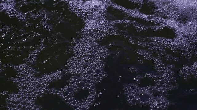 Close up of churning dark water and foam bubbles