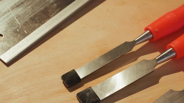 Close up view of woodworking tools including chisels ruler on wooden surface. Hand selects tool from set chisel bench joiner workshop equipment craftsmanship