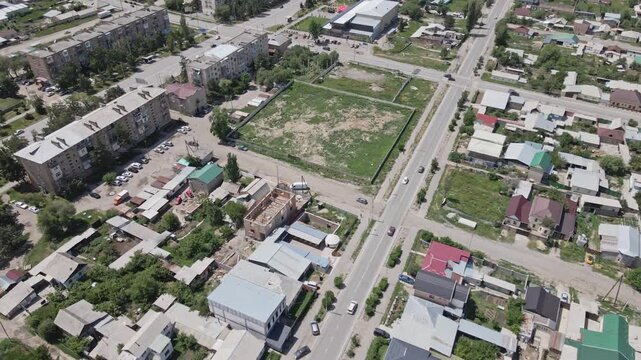 Aerial drone reveal of Karakol city from Soviet-era apartment buildings to surrounding fields and countryside in Kyrgyzstan