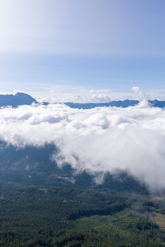 Sunlit Mountain Peaks Above Puffy Clouds Over Forested Valley Near Chilliwack, British Columbia, Canada