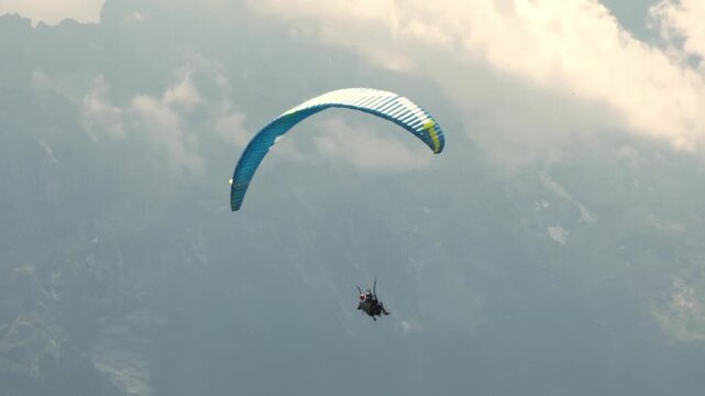 Tandem paragliding flight over Grindelwald near First mountain, Switzerland. Professional pilot and passenger flying above scenic alpine landscape. Concept of adventure tourism, outdoor recreation.