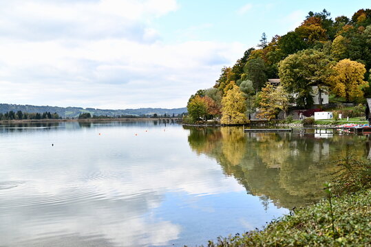 Panoramic autumn forest reflection on peaceful alpine lake Kochelsee Germany for travel brochure