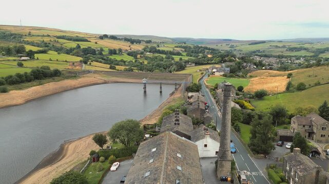 Aerial view of a dam and village nestled in green hills. Leeming_Village, Halifax, West Yorkshire, Wind Farm, turbines,