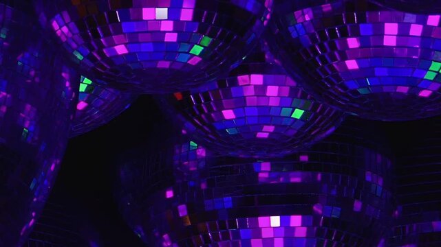 Blue and Green Lighting on a Group of Mirrored Disco Balls. Multiple mirrored spheres fill a dark interior as mosaic tiles catch changing colored light and create shimmering abstract reflections.