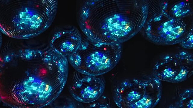 Colorful Disco Balls Reflect Blue and Green Light in a Dark Interior. Reflective spheres fill the dark interior while tiled mirror surfaces scatter changing light into colorful abstract patterns.