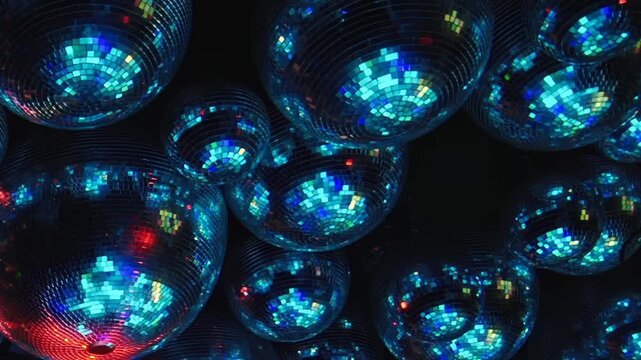 Disco Ball Reflections Glow in Purple and Blue Light. Multiple mirrored spheres fill a dark interior as mosaic tiles catch changing colored light and create shimmering abstract reflections.