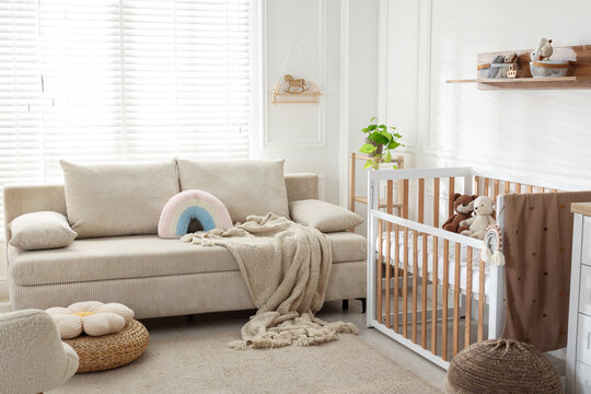 Stylish room with baby's crib and sofa. Interior design