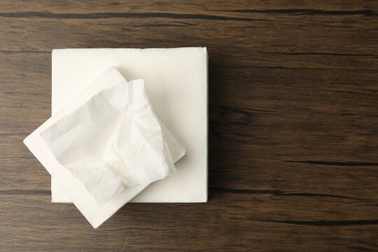 Stack of paper tissues and used napkin on wooden table, top view. Space for text