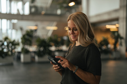 Professional woman using smartphone in modern office building