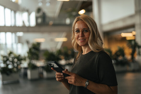 Professional woman using smartphone in modern office building