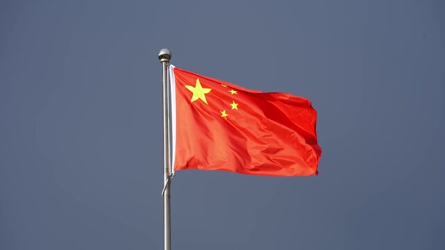 red chinese national flag waving against blue sky background