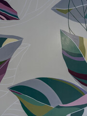  Hand-painted modern mural featuring abstract tropical leaves in purple, green, and pink against a gray background © Irene frontado