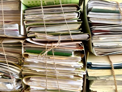 A close-up view of stacked and bound paper documents, folders, and archives tightly secured with twine, representing bureaucracy, administrative paperwork, and historical records.