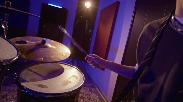 Teenage boy spinning drumstick and playing drums during rehearsal in music studio. Footage fits music education campaigns, youth entertainment ads, and creative arts promotions