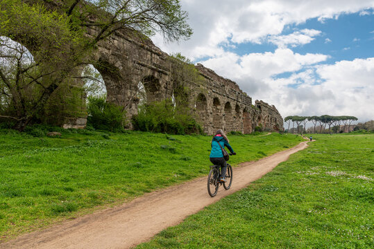 A Young Woman Cycling Along the Scenic Path Toward the Acqua Felice Aqueduct in the Parco degli Acquedotti, Rome