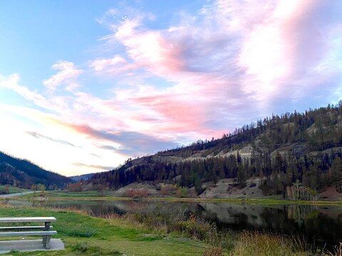Beautiful pink sunrise over forest, river and foothills with picnic table in park