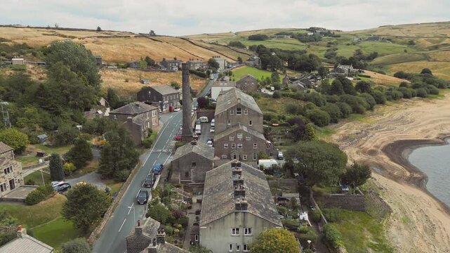 Aerial view shows quiet village beside calm lake. Leeming_Village, Halifax, West Yorkshire, Wind Farm, turbines,