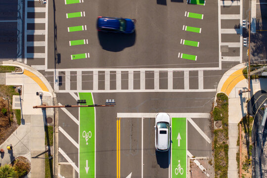Dynamic street scene in Sarasota with people walking across a pedestrian crossing while traffic lights control the flow of vehicles at a busy junction.