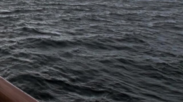 Arctic Ocean Ship Navigating Dark Polar Waters Across Open Water. Dark swells move across the cold water while the distant polar horizon remains clearly visible.