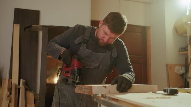 Carpenter operates red jigsaw on wooden material within workshop setting. scene includes various lumber pieces in background emphasizing woodworking activity and tools
