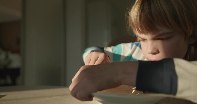 Close-up kid boy eats breakfast lunch in kitchen. 4K 10-bit