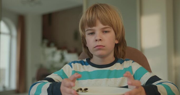 Close-up kid boy eats breakfast lunch in kitchen. 4K 10-bit