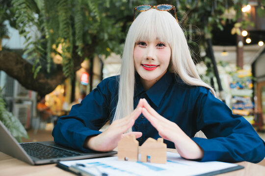 Happy confident woman holding wooden house model with joy for real estate investment insurance safety protection concept