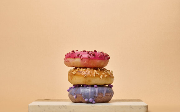 Stack of three multicolored donuts with glaze and sprinkles on a board