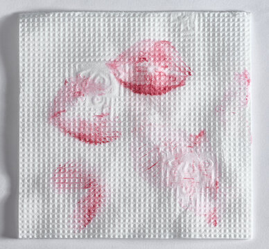 Lipstick and kiss prints on a white textured paper napkin