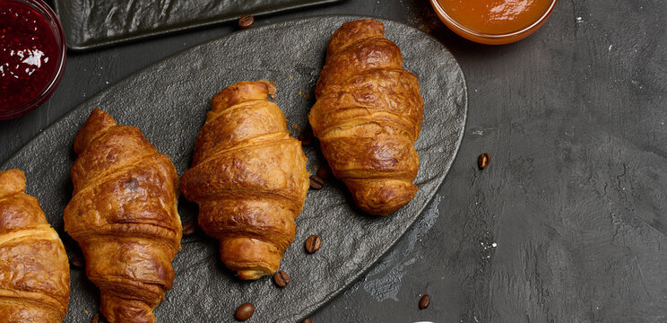 Freshly baked croissants on a black table, delicious breakfast
